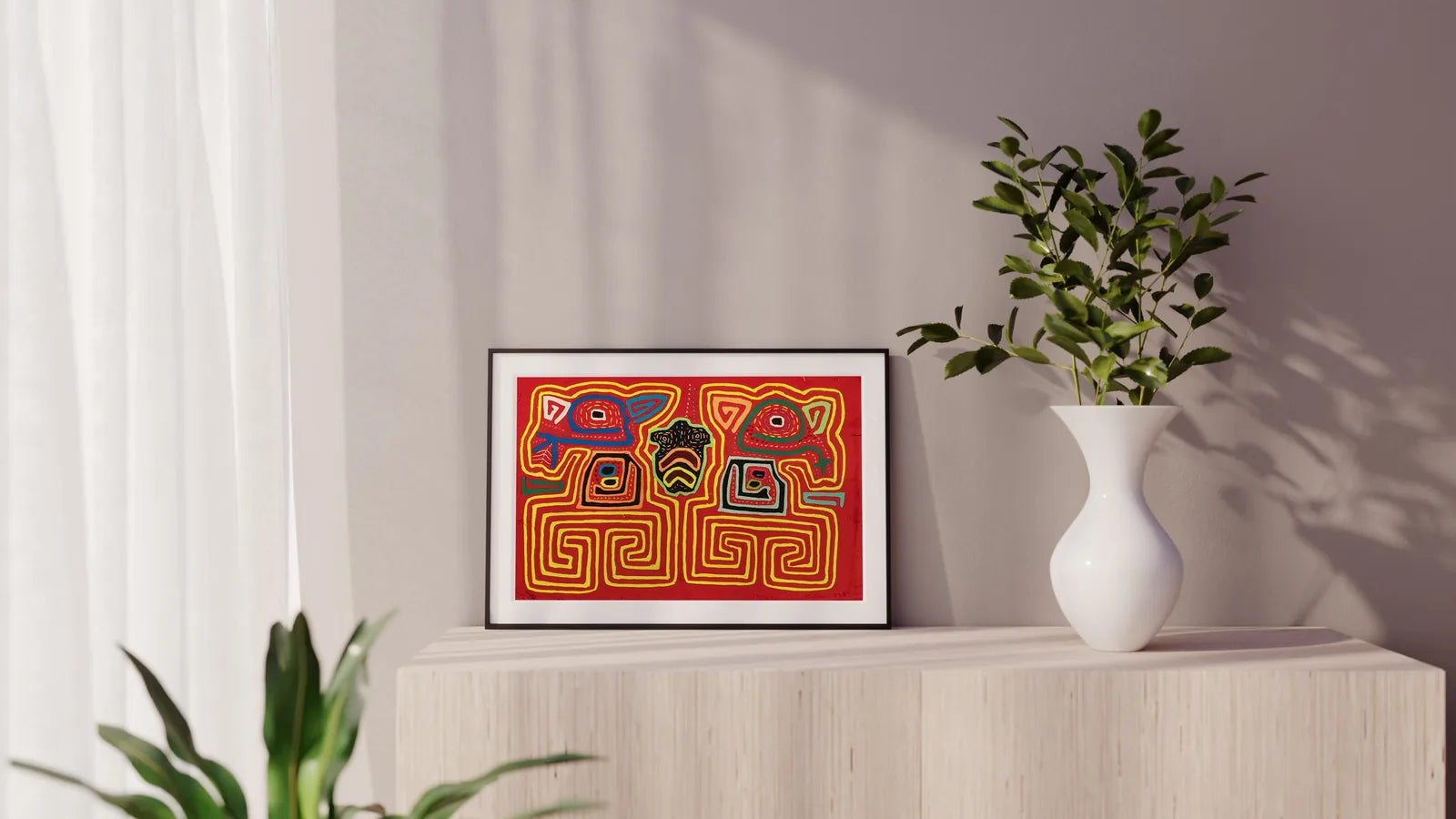 Hand-stitched red Mola tapestry featuring colorful geometric patterns, displayed in a modern setting with greenery.