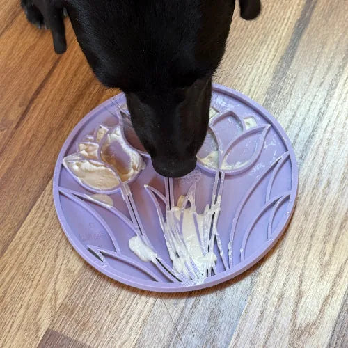 Light purple tulip design lick mat with a dog enjoying soft treats, showcasing its textured surface.