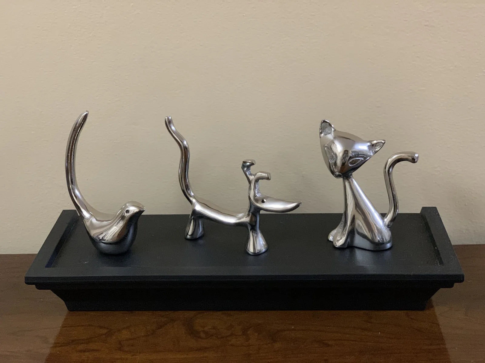 Glossy silver dog, cat, and bird ring holders on a black tray, showcasing modern design and elegant home decor appeal.