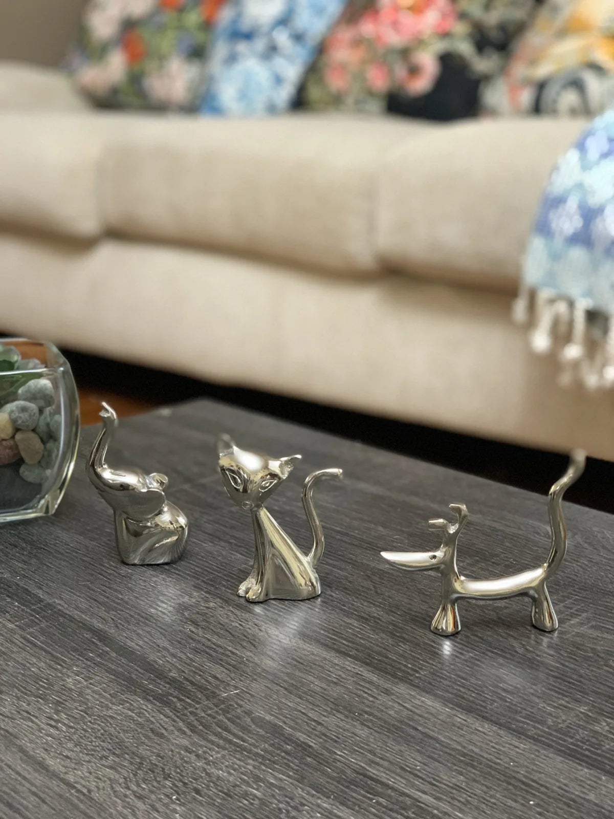 Silver dog, cat, and elephant ring holders on a dark tabletop, each featuring a glossy finish and unique design.