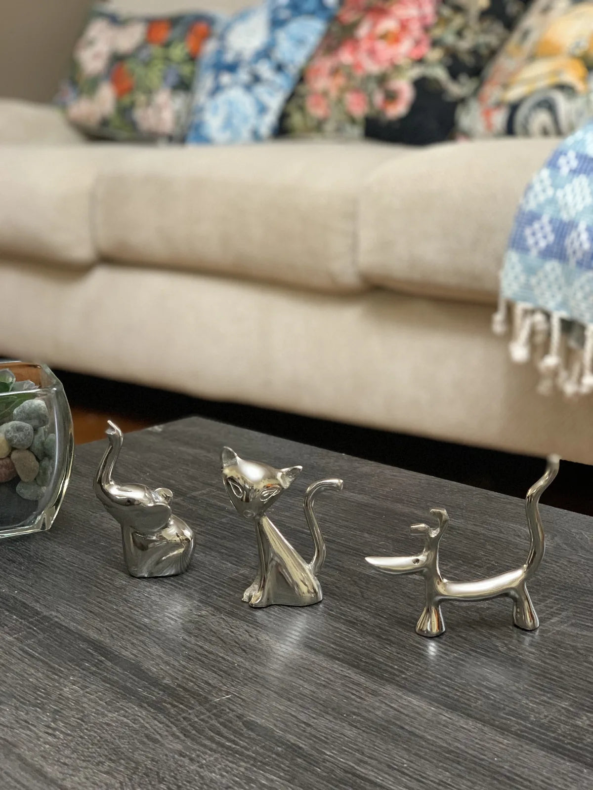 Shiny silver dog, cat, and elephant ring holders on a dark wooden surface, perfect for home decor and jewelry organization.