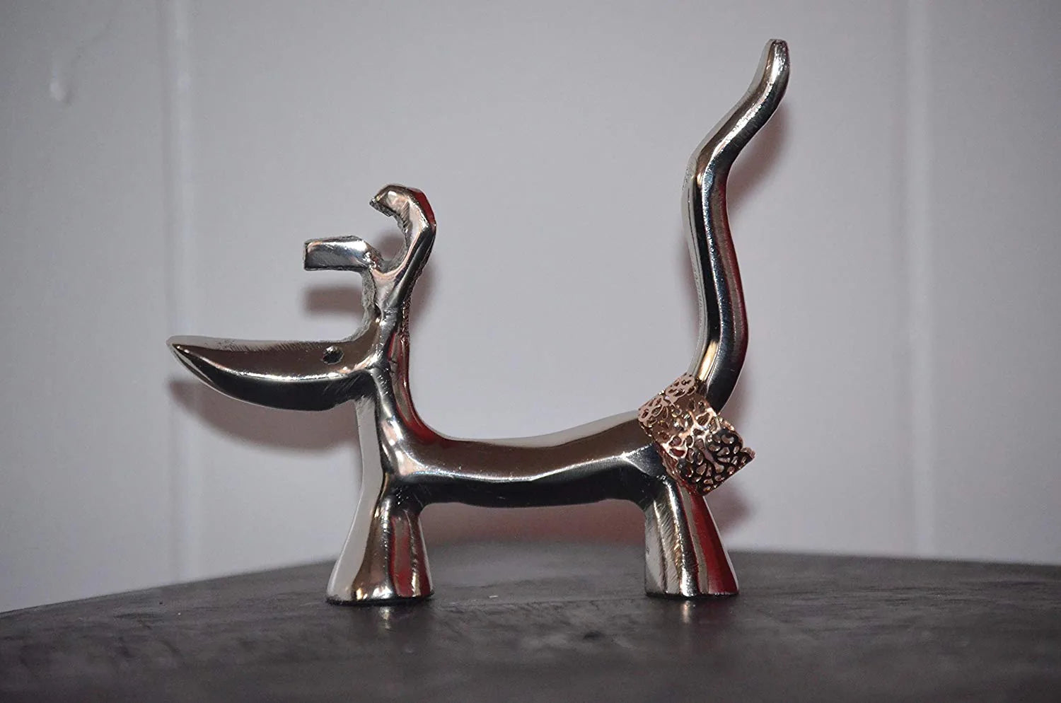 Handmade silver dog-shaped ring holder with a textured golden band, showcasing a modern design and sturdy base.