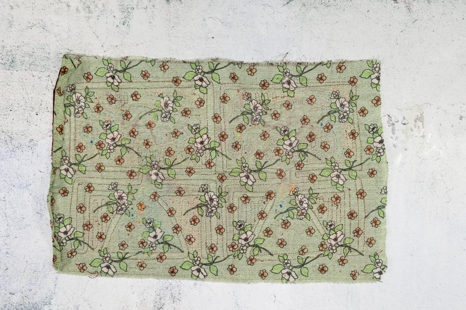 Hand-stitched green Panama Mola featuring vintage flowers and leaves in pink and brown tones on textured fabric.