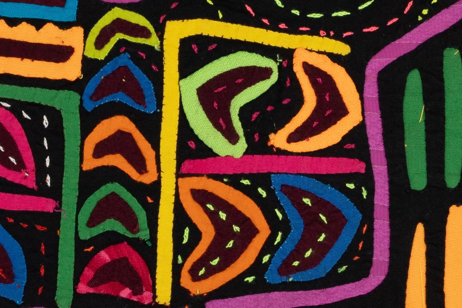 Colorful geometric patterns in vibrant pink, green, orange, and blue on a black background; handcrafted textiles from Panama.
