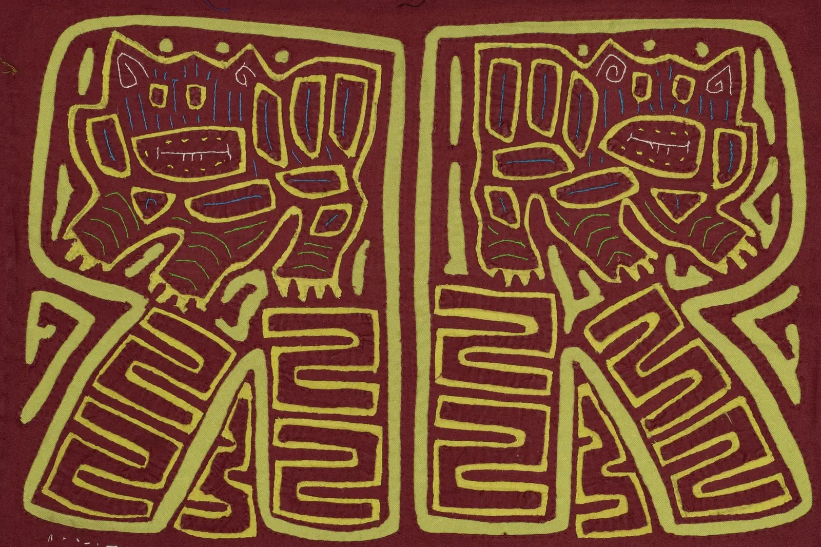 Hand-stitched vintage Mola featuring playful puppy designs in burgundy and green on a textile background.