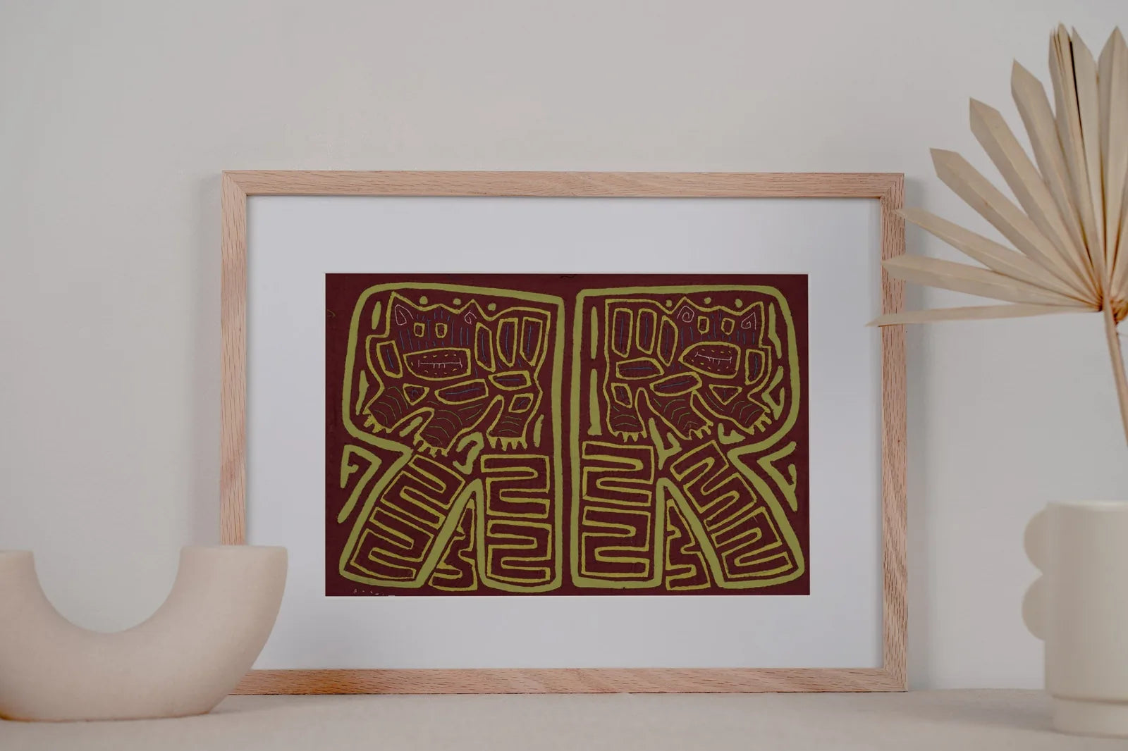 Vintage burgundy and green hand-stitched Mola featuring playful dog designs, framed against a neutral background.