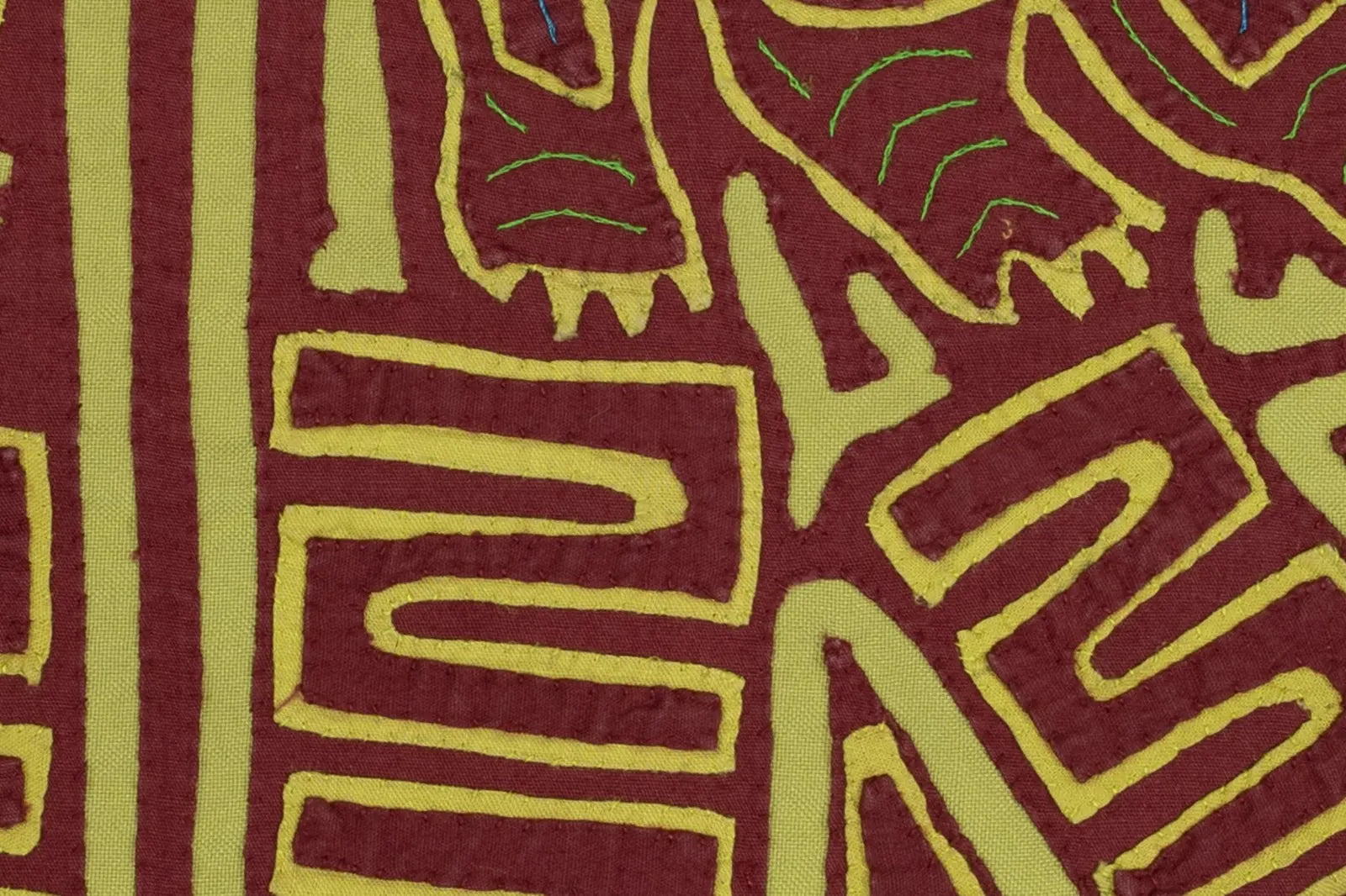 Hand-stitched vintage burgundy and green mola featuring playful geometric patterns, crafted by indigenous artisans in Panama.