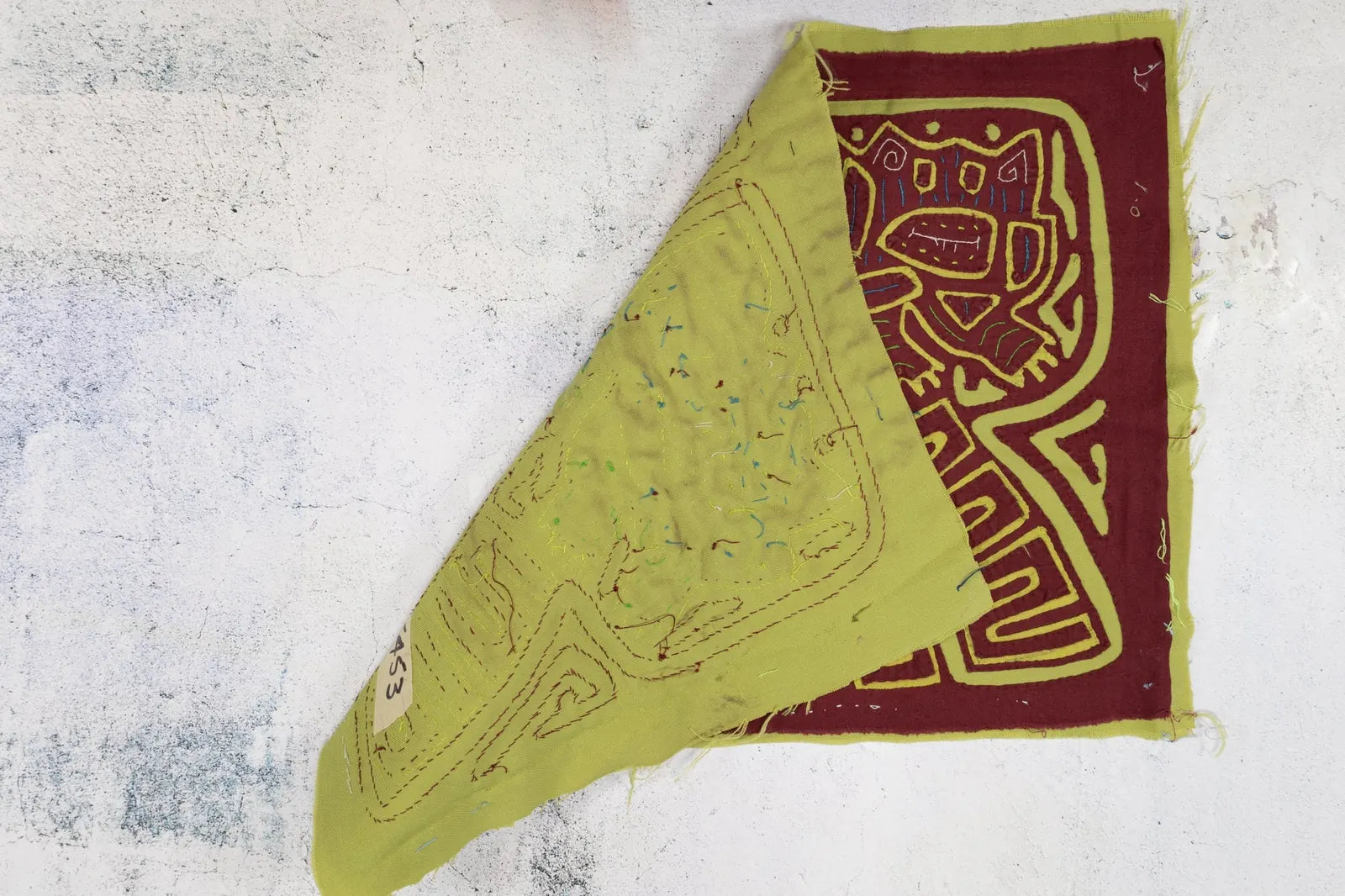 Hand-stitched vintage Mola featuring playful dog designs in burgundy and green, showcasing intricate geometric patterns.