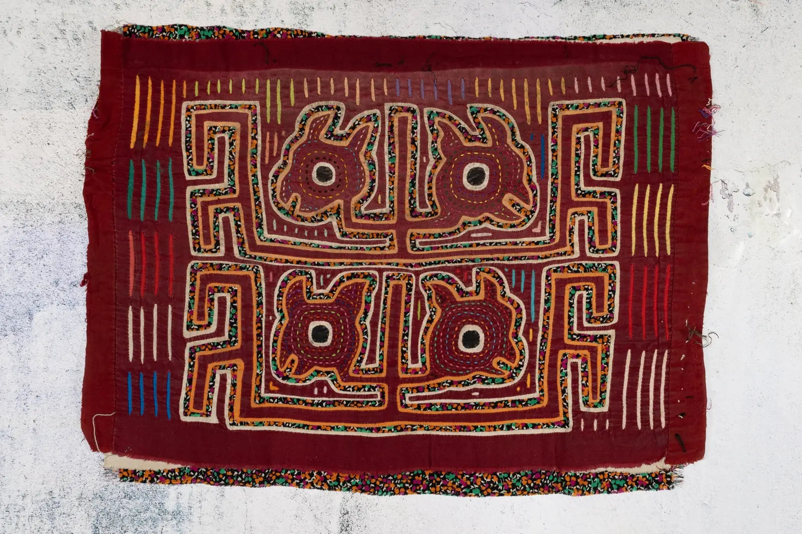 Vintage burgundy Mola featuring intricate hand-stitched designs of yapping puppies on colorful textile.