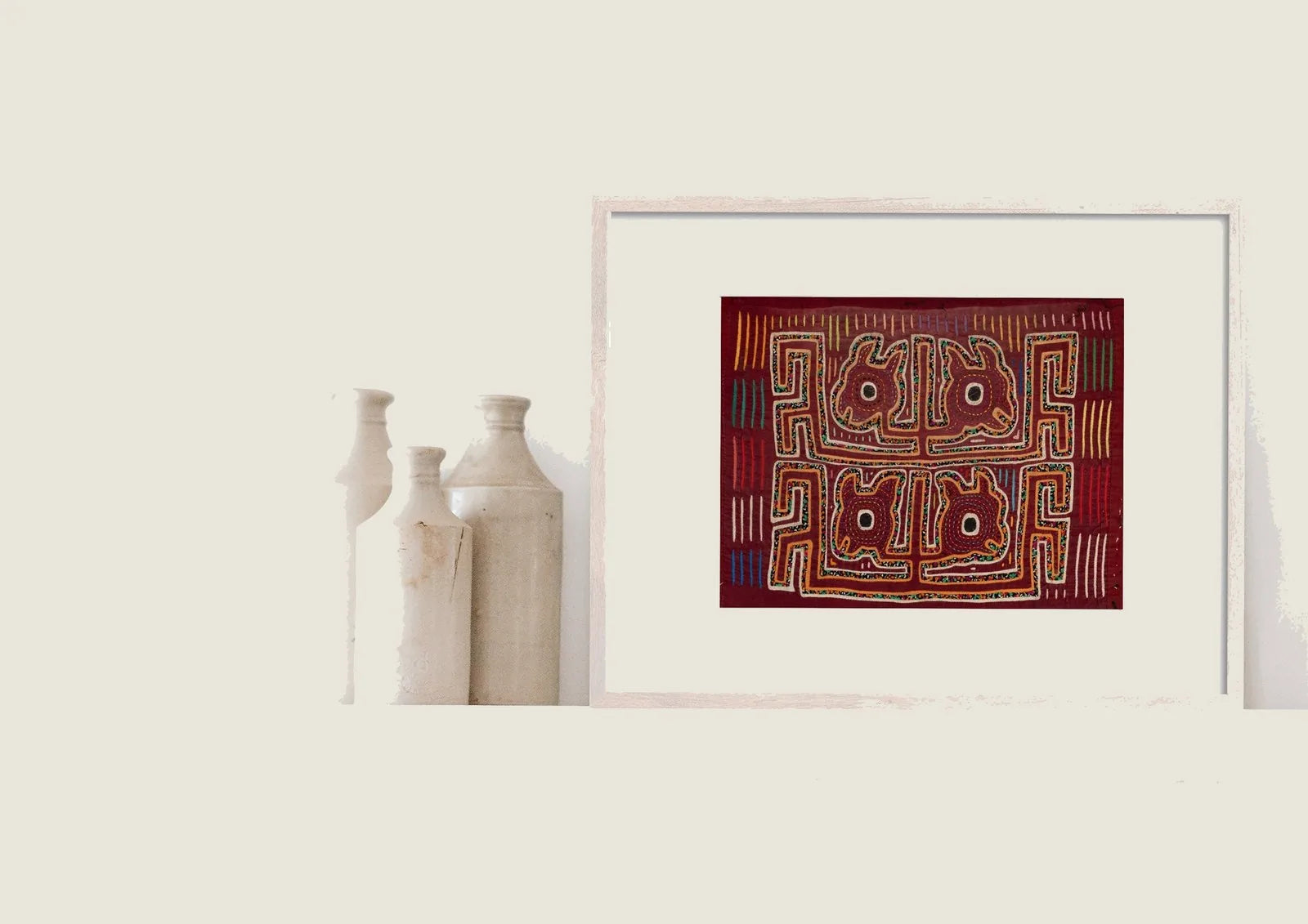 Hand-stitched vintage burgundy Mola featuring a yapping puppy design, framed and displayed alongside decorative vases.