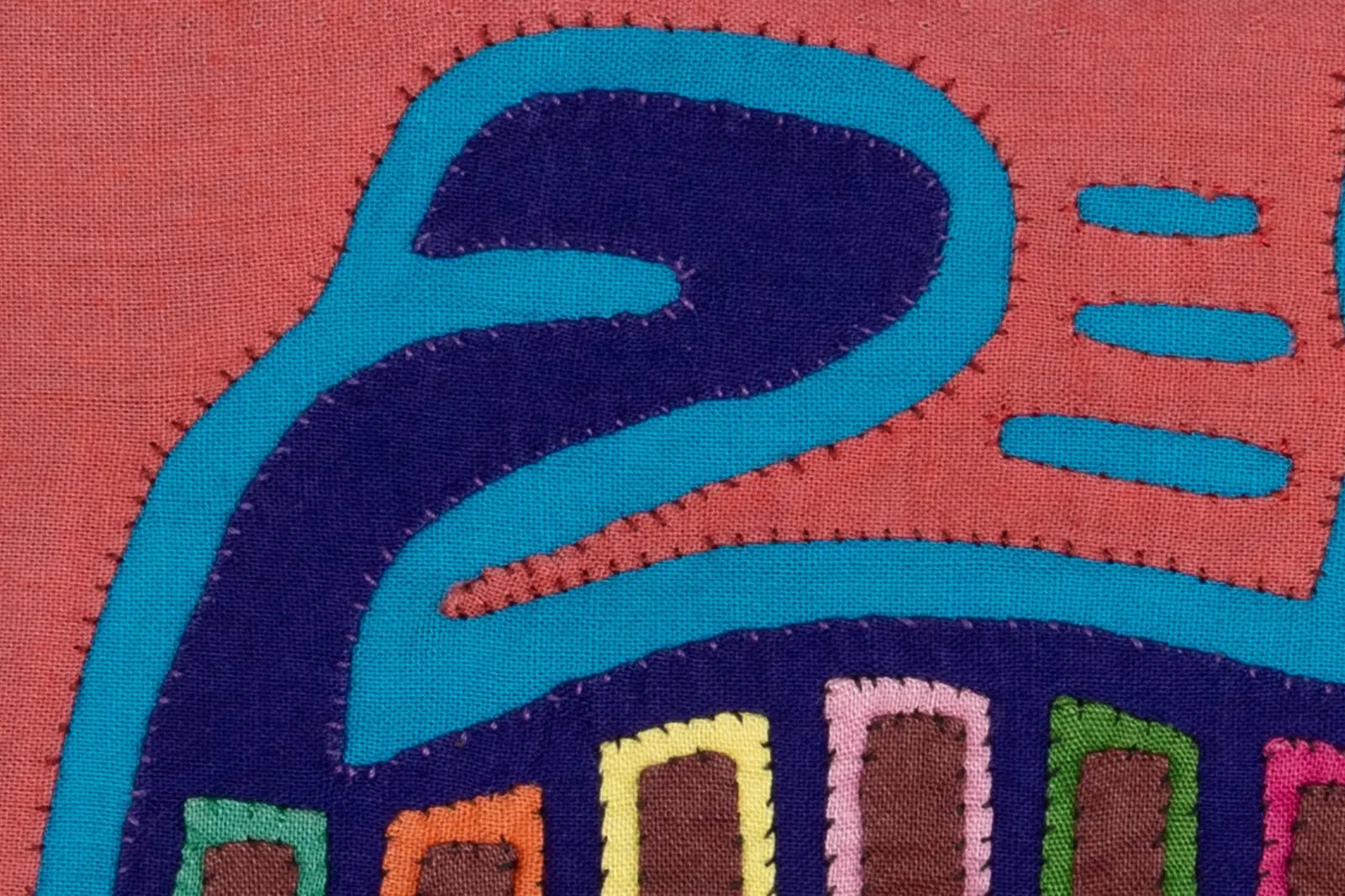 Hand-stitched pink and purple textile art featuring vibrant geometric patterns, reflecting the Guna artisan's craftsmanship.