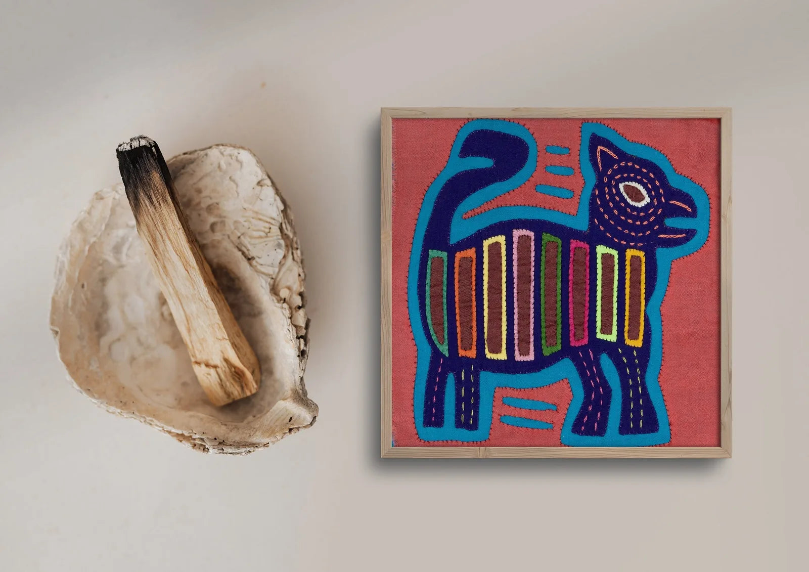 Vintage pink and purple dog Mola tapestry with geometric patterns, framed and displayed with a natural wooden stick.