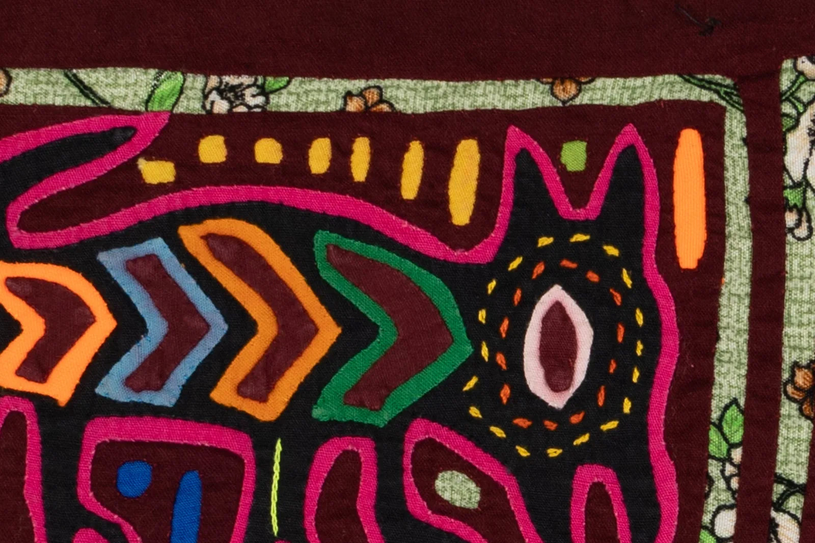 Colorful hand-stitched Mola featuring a playful puppy design with vibrant patterns on a textured background.