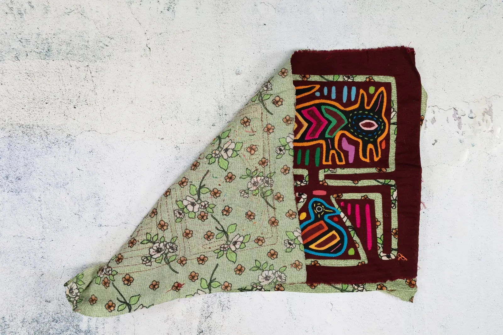 Vintage puppy and bird design on colorful hand-stitched Mola tapestry with floral background in shades of green and burgundy.