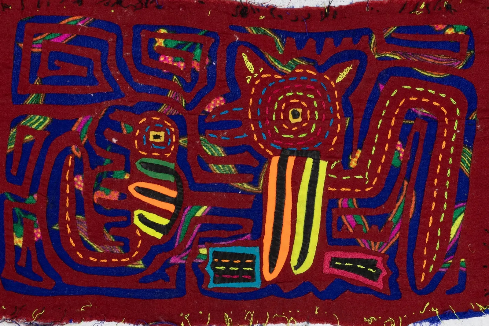 Hand-stitched, colorful Panama Mola featuring a puppy and gecko design on rich red fabric, showcasing traditional textile...
