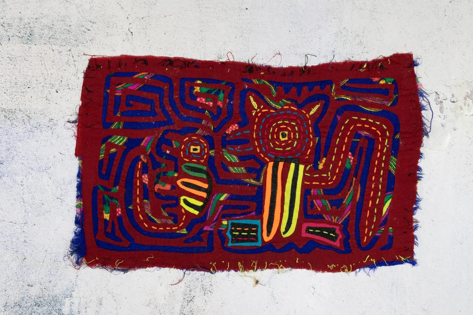 Hand-stitched red Panama Mola featuring vibrant geometric designs of a puppy and gecko, showcasing traditional textile art.
