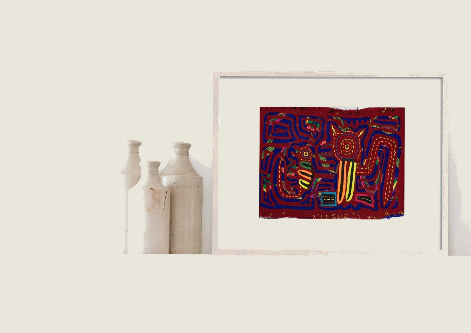 Hand-stitched Molas featuring vibrant geometric designs of a puppy and gecko on a deep red background, framed decoratively.