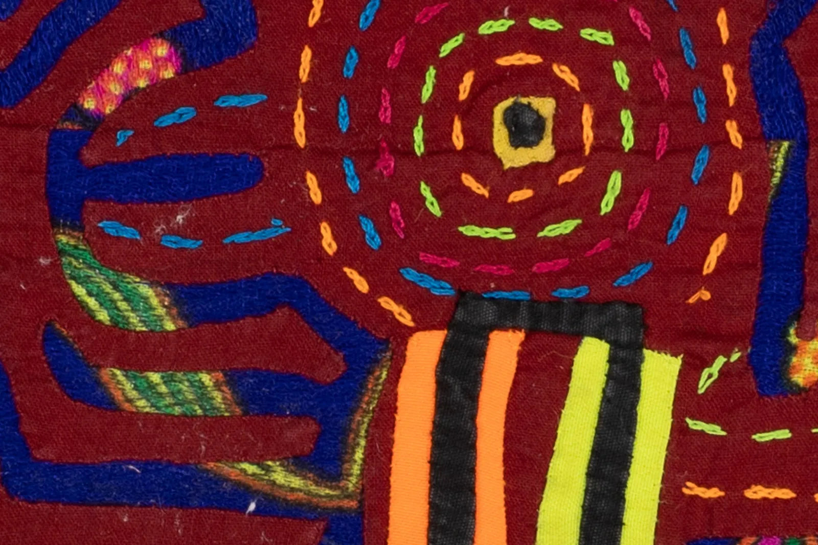 Colorful hand-stitched textile featuring vibrant geometric patterns on a red background, showcasing traditional Panama Mol...