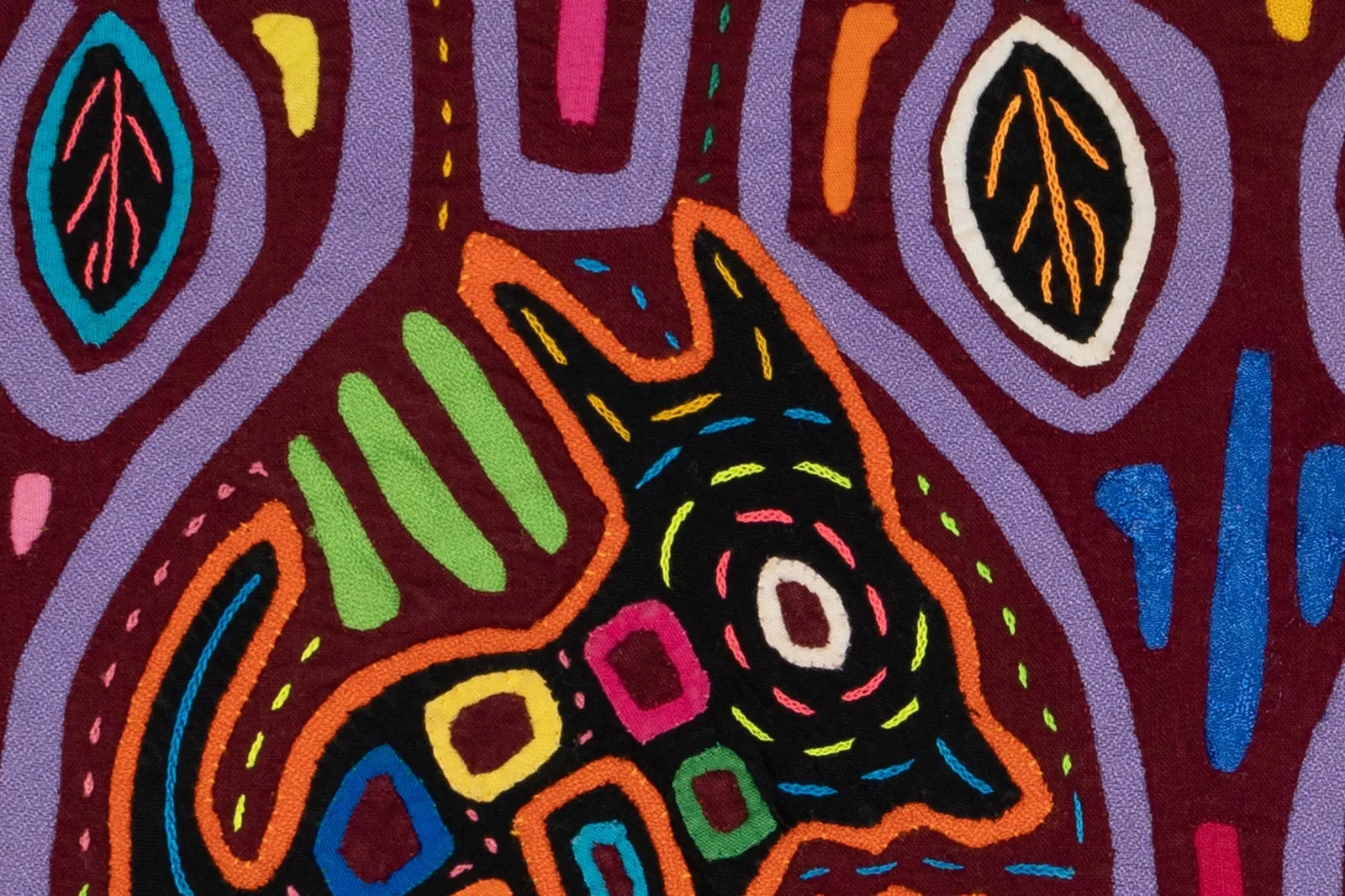 Colorful hand-stitched tapestry featuring a black dog amidst vibrant patterns of green, purple, and pink.