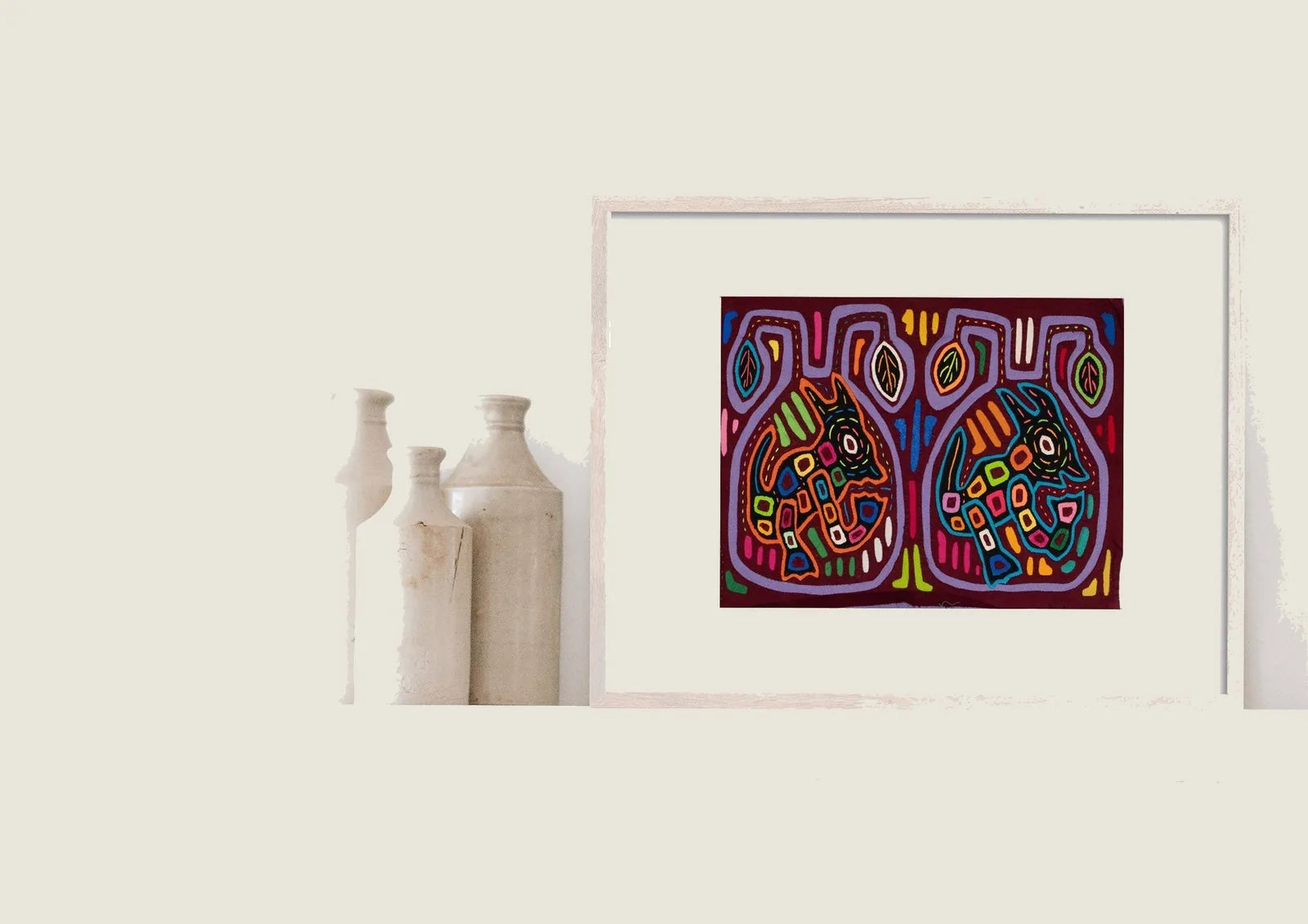 Colorful, hand-stitched Molas featuring two vibrant puppy designs on a dark background, framed and displayed on a shelf.