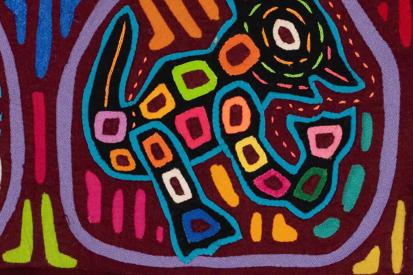 Colorful hand-stitched textile art featuring a playful puppy in bright hues against a deep maroon background.