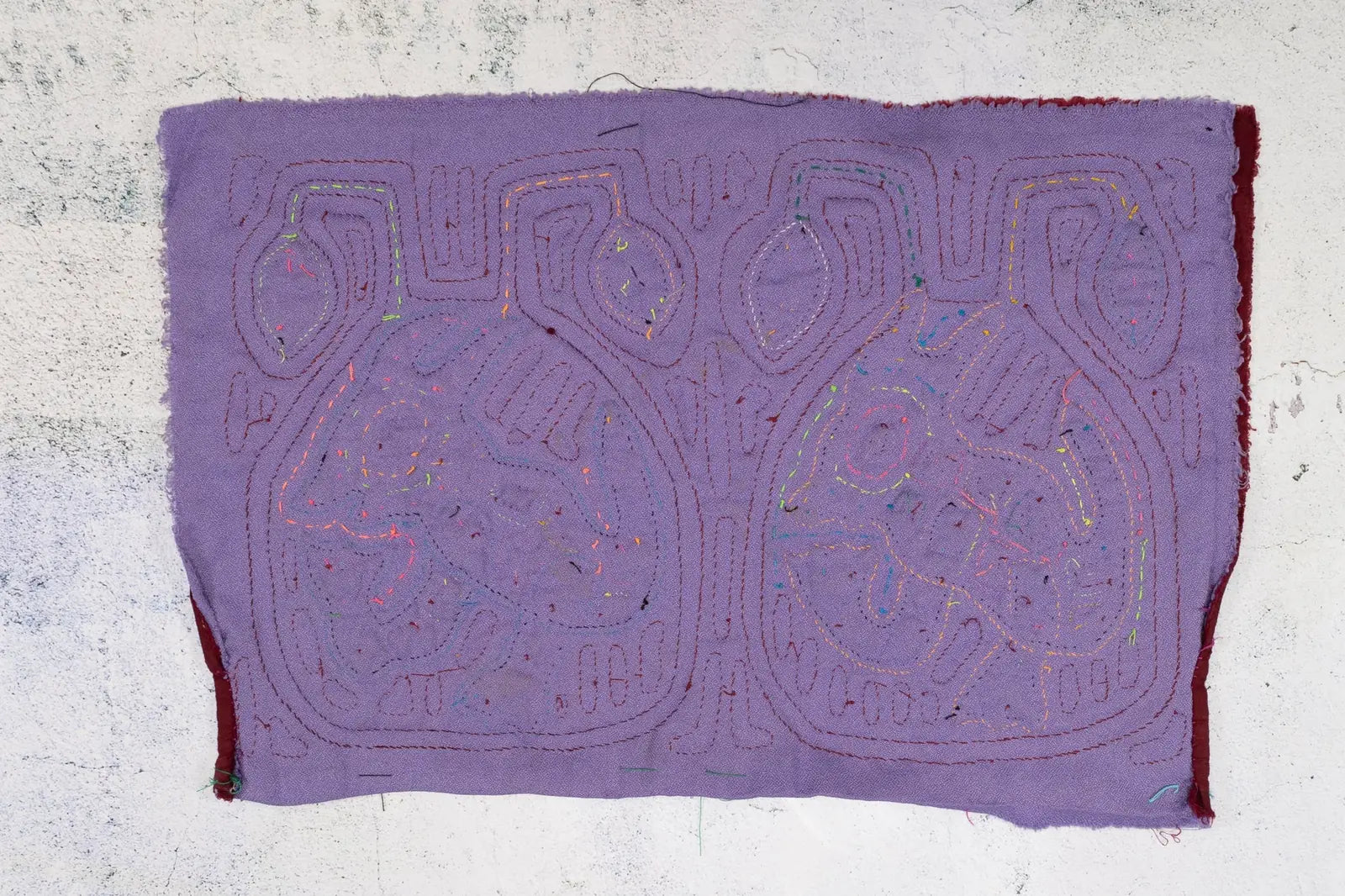 Colorful hand-stitched textile art featuring whimsical dog designs on a purple background, showcasing traditional Guna cra...