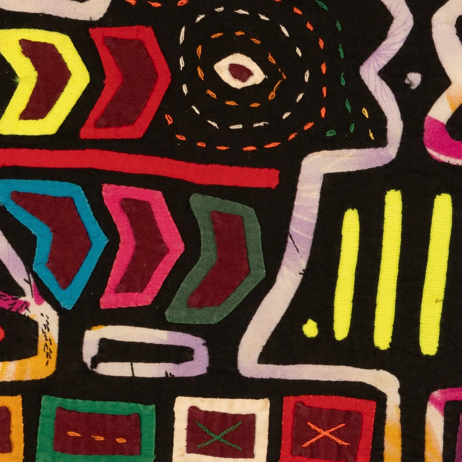 Colorful geometric patterns in vibrant hues of red, blue, green, and yellow on a black textile background.