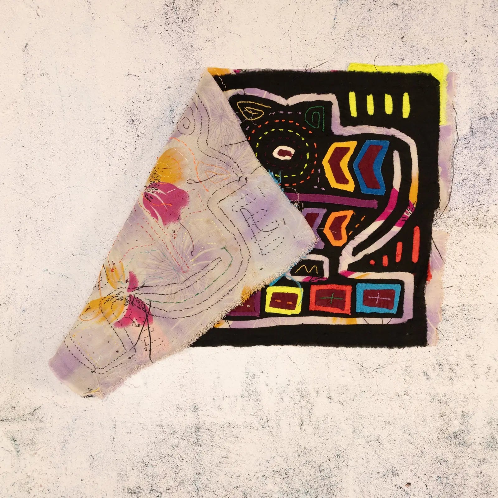 Colorful hand-stitched vintage mola featuring geometric patterns, showcasing a vibrant mix of purple and black fabric.