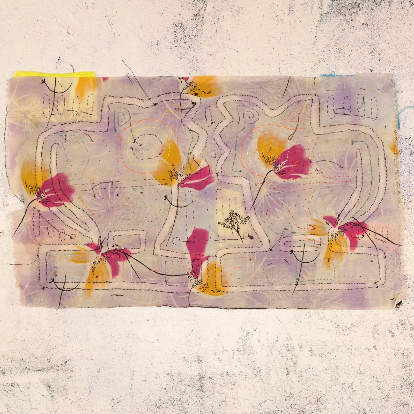 Colorful hand-stitched vintage mola textile featuring two puppy silhouettes surrounded by floral patterns in pastel hues.