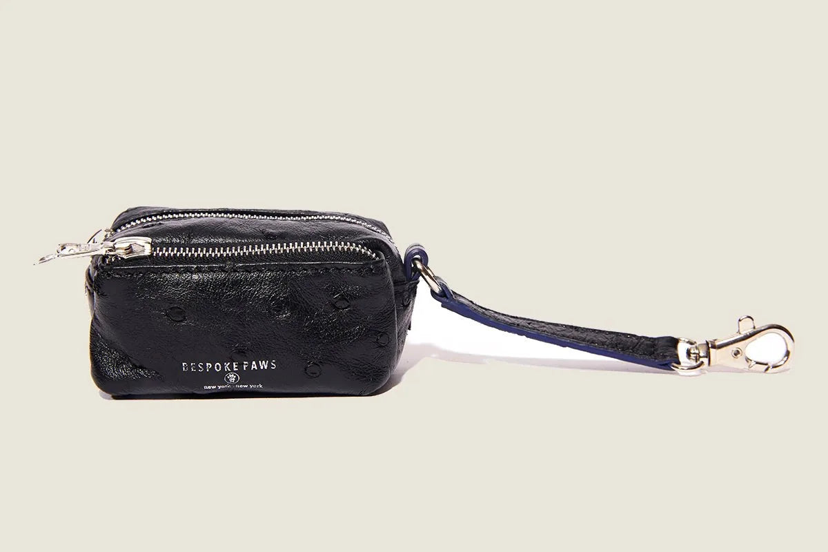 Black ostrich-pattern waste bag dispenser by BESPOKE PAWS with a silver zipper and clip for leashes or belts.
