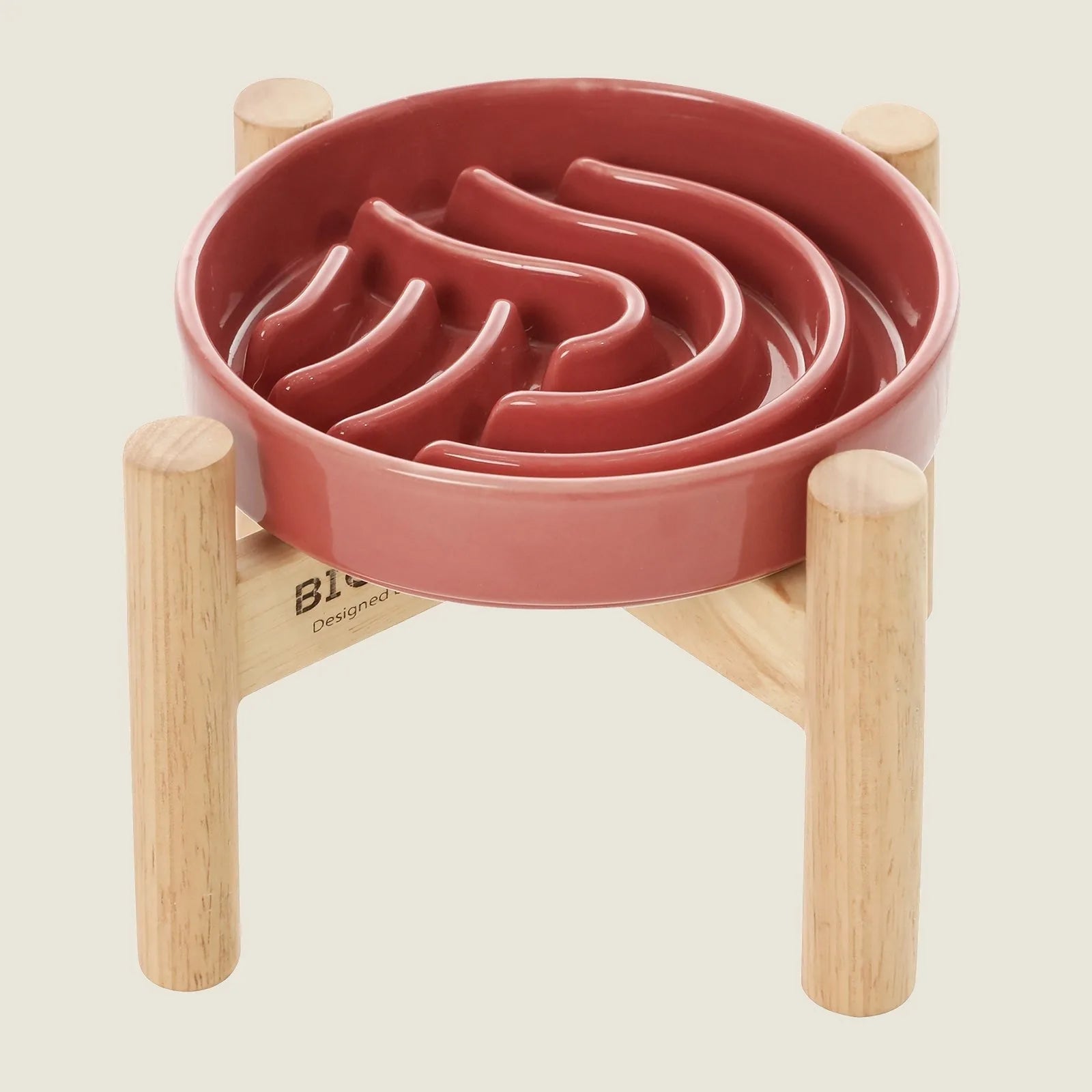 Slow feeder dog bowl in pink ceramic with wavy pattern, elevated on a beige wooden stand for easy access.