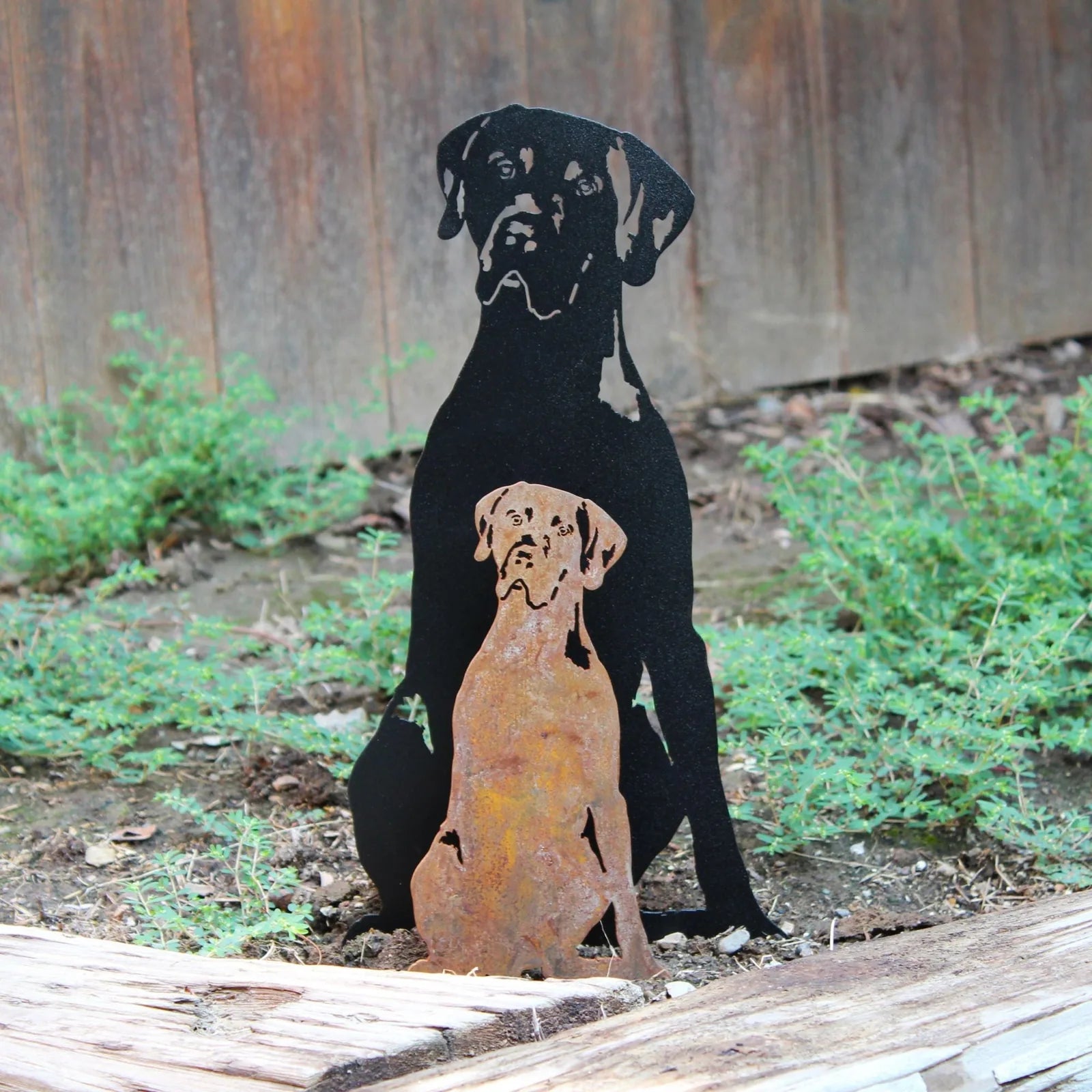 Weimaraner metal silhouette in black and rust, set in a garden with greenery, showcasing durable outdoor decor.