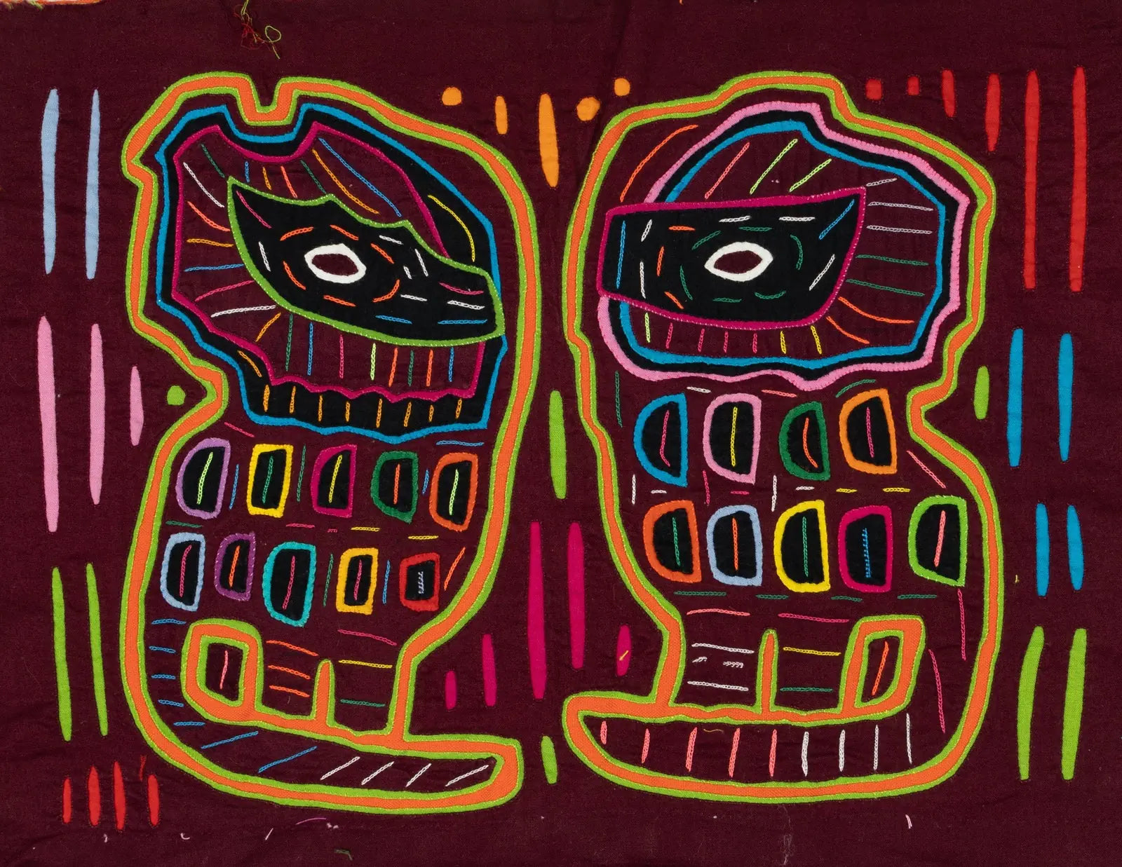 Vibrant hand-stitched Mola tapestry featuring two abstract dog shapes in pink, blue, and green on a maroon background.