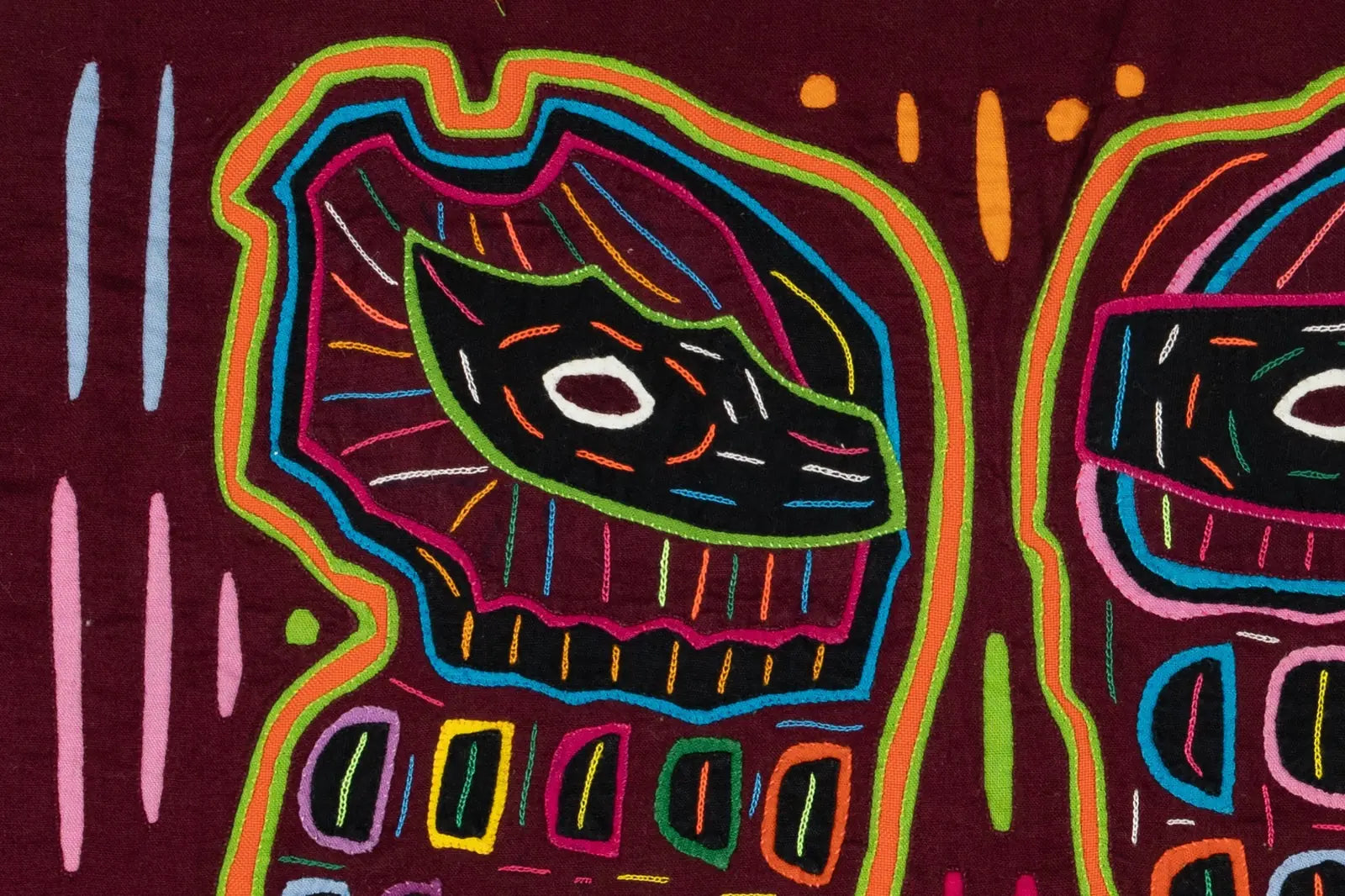 Colorful abstract designs in vibrant threads on a maroon tapestry, showcasing intricate hand-stitching techniques.