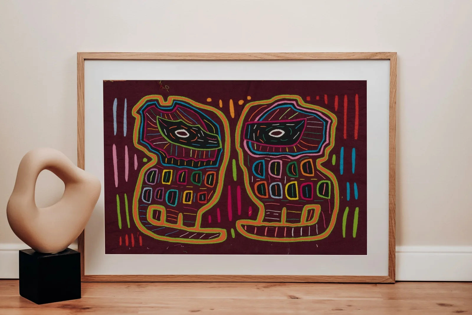 Colorful hand-stitched tapestry featuring geometric patterns and two stylized dog faces on a dark background.
