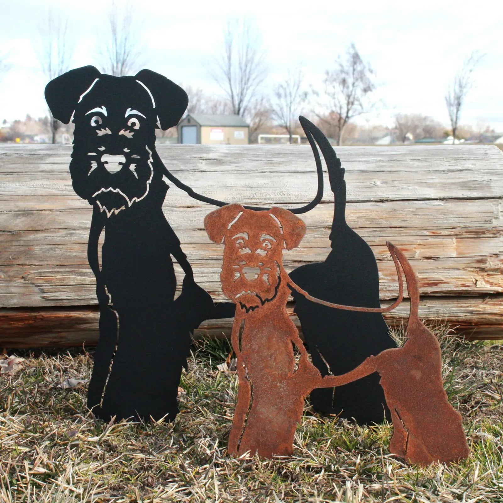 Welsh Terrier metal silhouette art in black and rust finishes, set against a natural outdoor backdrop.