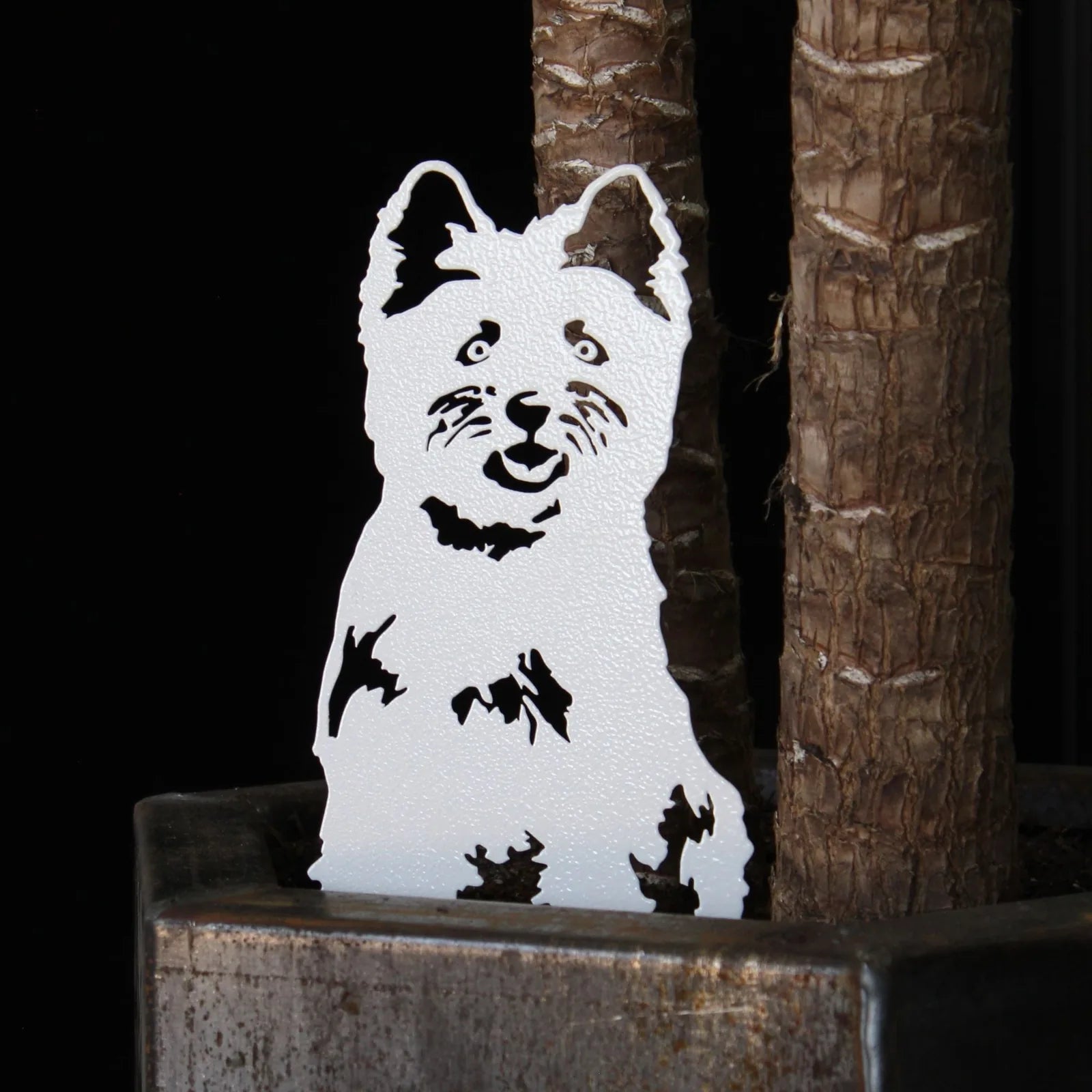 White West Highland Terrier metal silhouette against a dark background, showcased in a planter highlighting its detailed d...