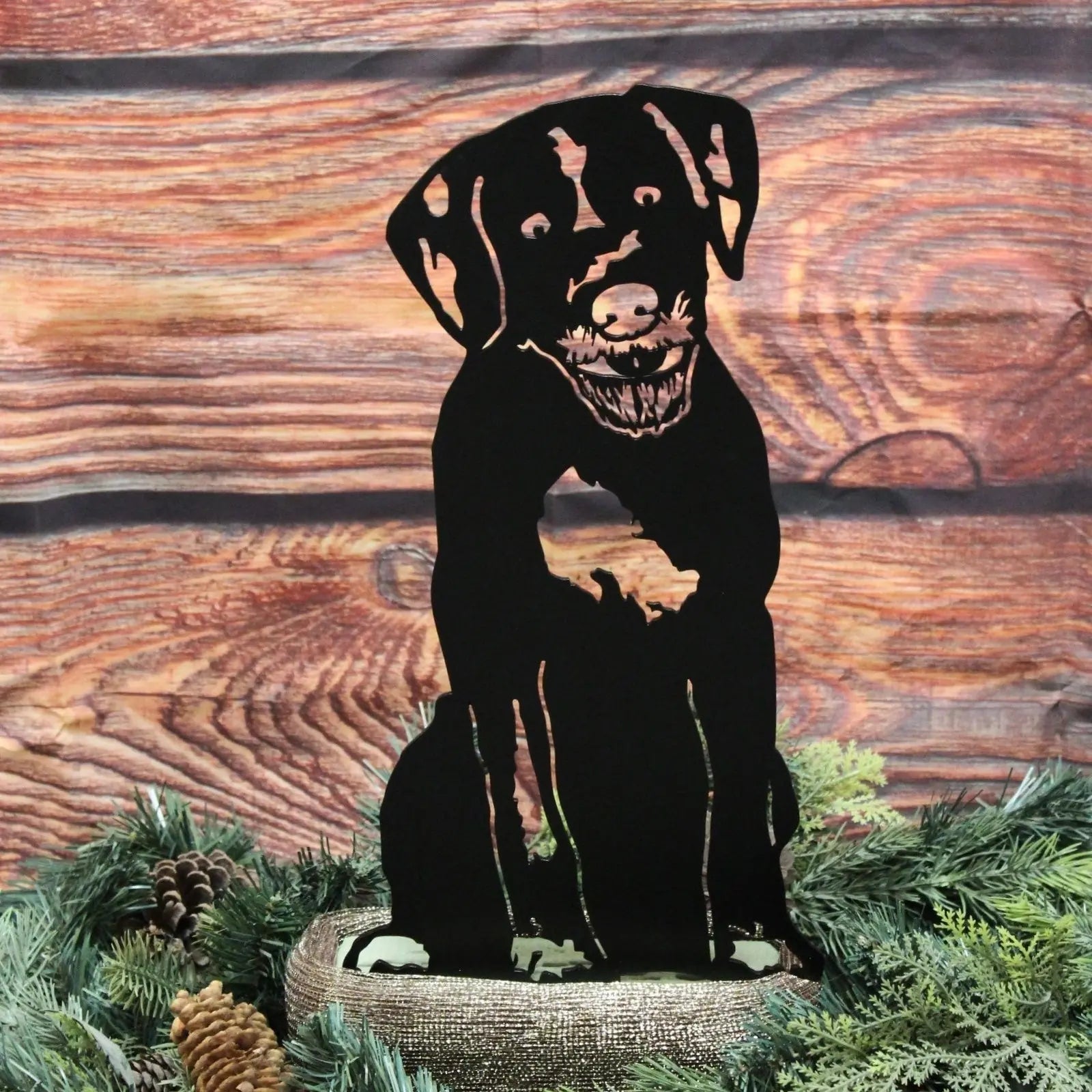 Black metal silhouette of a Wirehaired Pointing Griffon resting on natural greenery, ideal for outdoor decor.