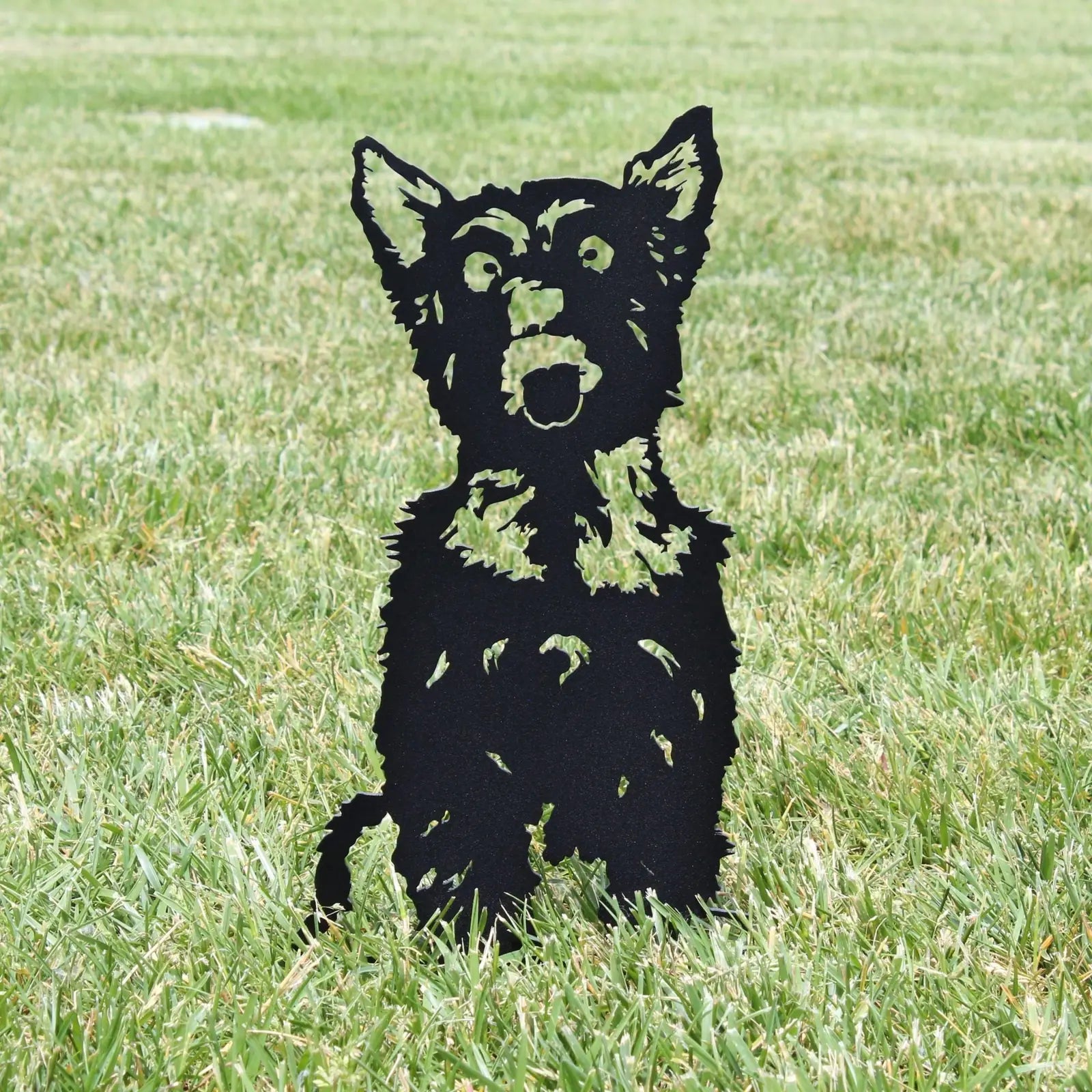 Black metal silhouette of a Yorkshire Terrier standing on grass, designed for outdoor decoration and durability.