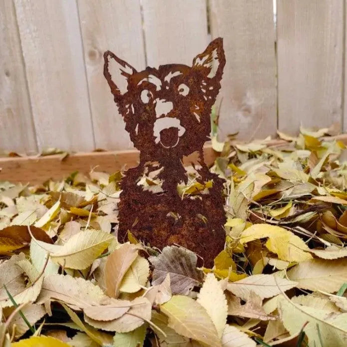 Rusty metal silhouette of a Yorkshire Terrier amidst colorful autumn leaves, adding charm to outdoor decor.